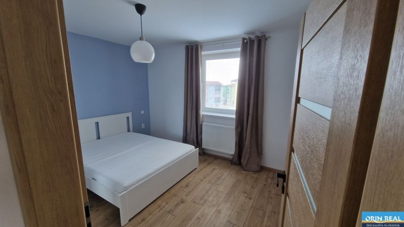 NOVÝ ZARIADENÝ BYT NA Muškáte - Spálňa v 2-izbovom byte s posteľou, lampou a oknom, krémové závesy.