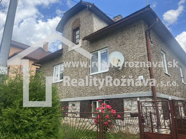 Rodinný dom zo záhradou - Rudná - Rodinný dom v Rudnej s textúrovanou fasádou, zeleným plotom a kvetmi v záhrade.