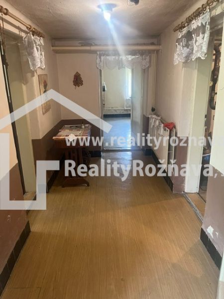 Rodinný dom zo záhradou - Rudná - Chodba v rodinnom dome s podlahou s dreveným dekorom, stolom a dekoráciami.