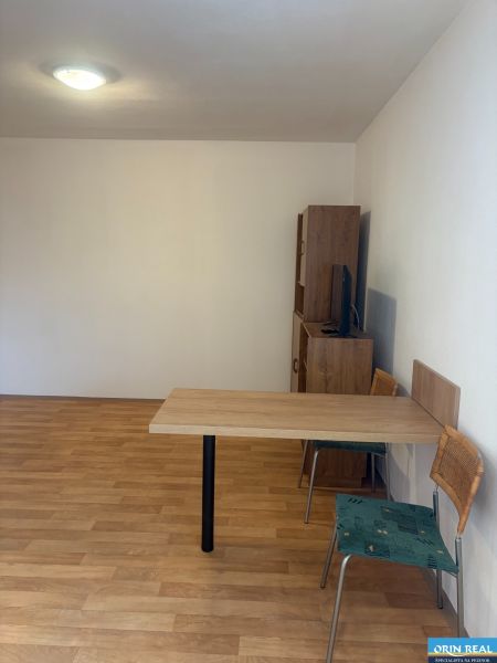ZARIADENÁ GARSONKA NA SEVERE - Garsónka s podlahou s dreveným dekorom, stolom a stoličkami.