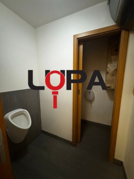 Podnikateľské priestory v  širšom centra mesta Nové Zámky, prízemie - Interiér obchodných priestorov s toaletou a tmavou podlahou s dreveným dekorom.