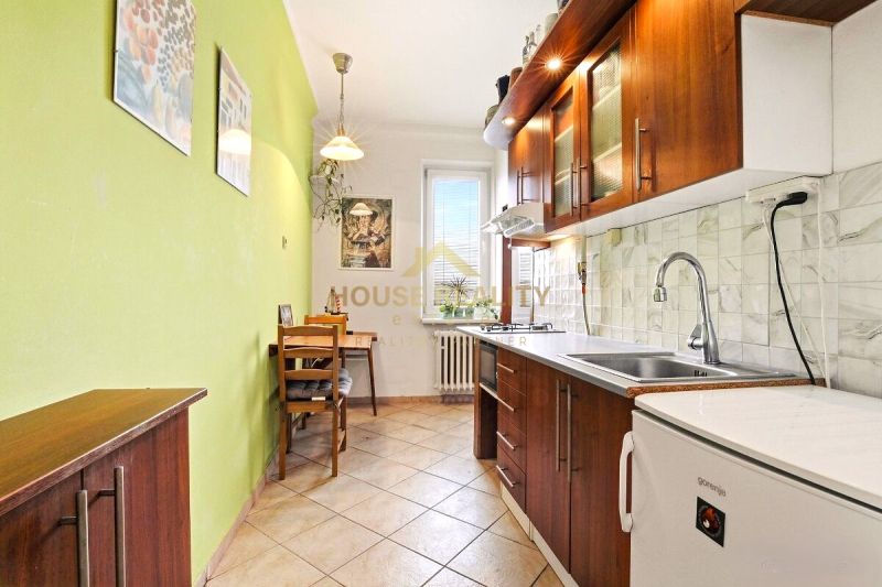 Predaj príjemný 2 izbový byt, Rovníková ulica, Bratislava II. Ružinov - Kuchyňa v 2-izbovom byte s dreveným dekorom a zelenou stenou, sedenie pri stole.