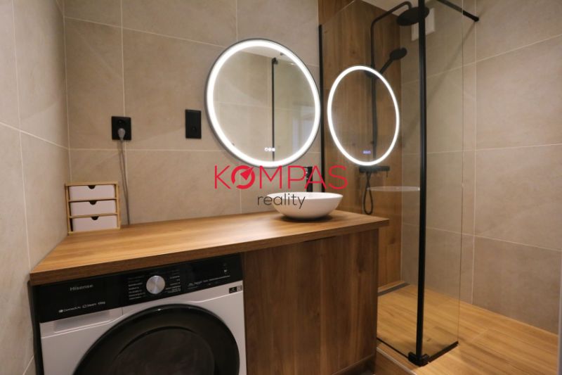MODERNÝ  2-IZB.BYT PO KOMPLETNEJ REKONŠTRUKCII, UŽ LEN BÝVAŤ - Kúpeľňa v 2-izbovom byte s umývadlom, sprchou a podlahou s dreveným dekorom.