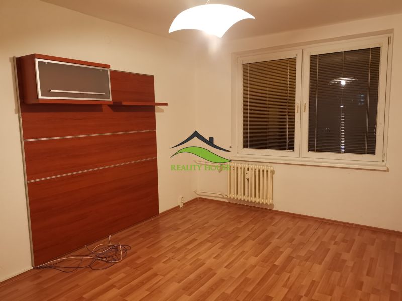 REZERVOVANÉ - Izba s podlahou s dreveným dekorom, bielymi stenami a nástennou skriňou v 3-izbovom byte.