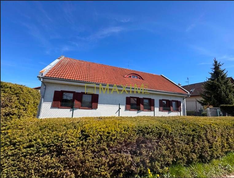 Rodinný dom v obci Kuchyňa - Rodinný dom v Kuchyni s červenou strechou, obklopený živým plotom.