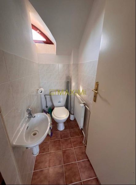 Rodinný dom v obci Kuchyňa - Kúpeľňa v rodinnom dome s WC, umývadlom a dlažbou v hnedých odtieňoch.