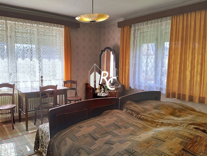Rodinný dom, Sučany - Spálňa v rodinnom dome s posteľou, stolíkom, stoličkami a záclonami.
