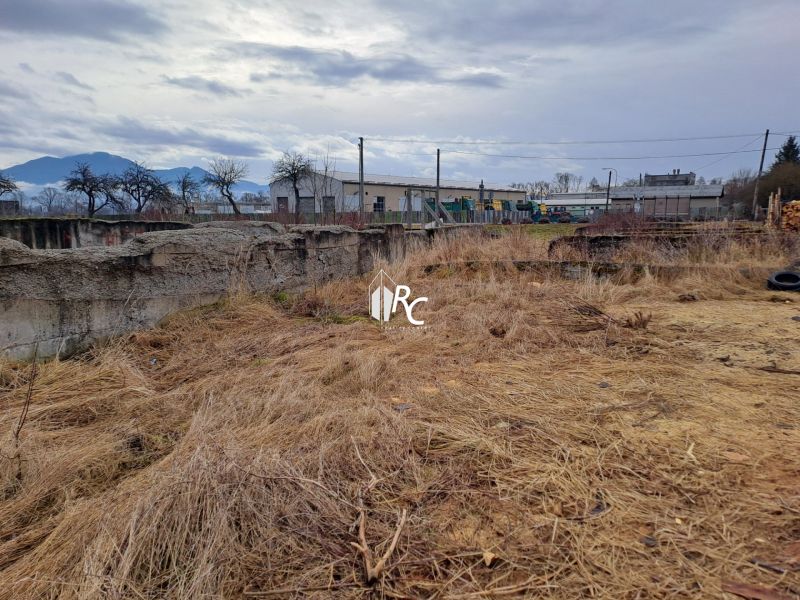 Stavebný pozemok 2 335 m² v obci Valča  - Pozemky na bývanie vo Valči s výhľadom na hory a starou budovou v diaľke.
