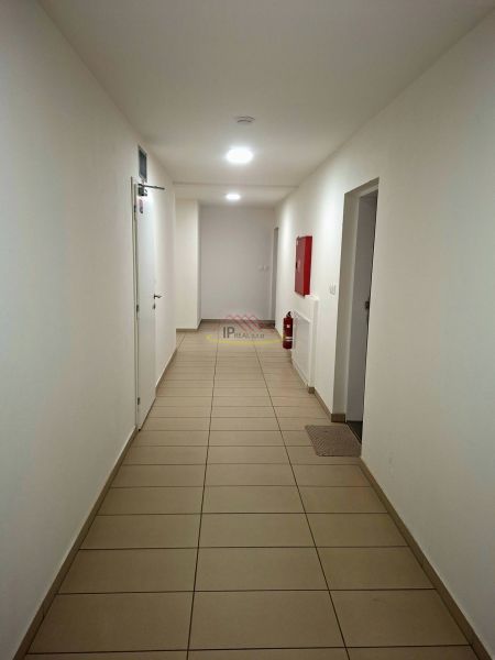 Priestranná garzónka s balkónom v novostavbe. - Chodba s bielymi stenami, dlažbou a núdzovým vybavením v Garsónke.