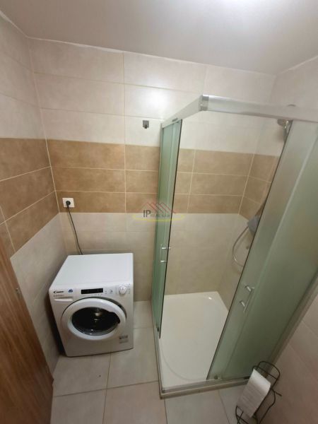 Priestranná garzónka s balkónom v novostavbe. - Kúpeľňa v garsónke s práčkou a sprchovým kútom.