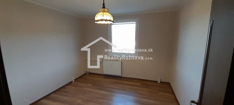 Pekný 2 izbový byt s balkónom na prenájom. - Izba v 2-izbovom byte s podlahou s dreveným dekorom a svetlom nad radiátorom.