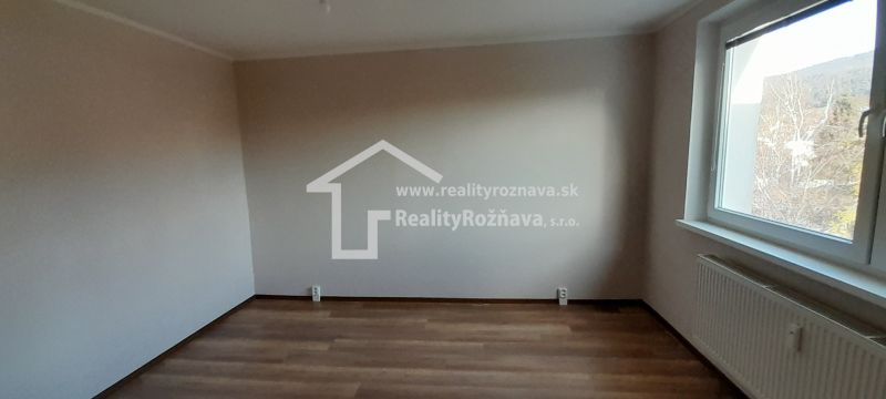 Pekný 2 izbový byt s balkónom na prenájom. - Izba v 2-izbovom byte s podlahou s dreveným dekorom a veľkým oknom.