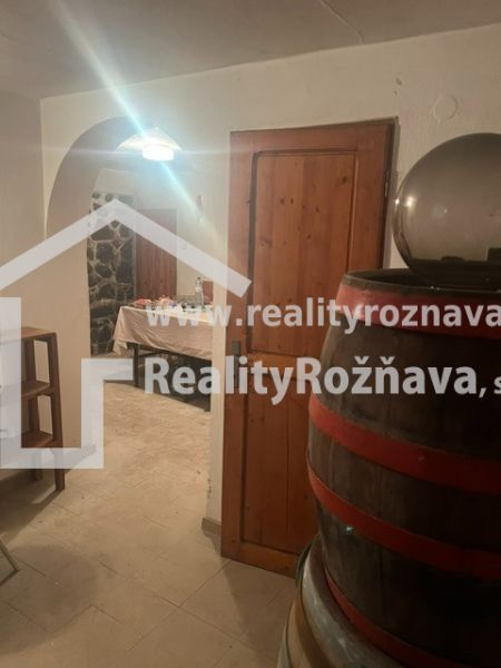 PREDAJ/ Krásna chalupa s vinicou/Jablonov nad Turňou - Sklep chaty s dreveným sudom a kamennou stenou, vidieť stôl v pozadí.