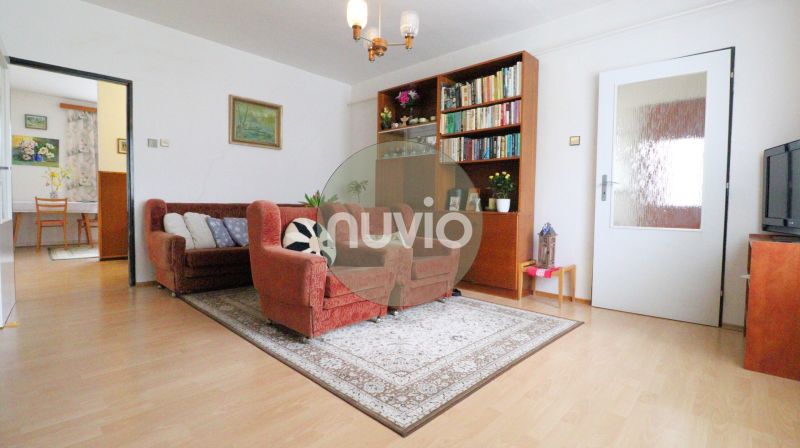 STRÁNE - 5 izbový rodinný dom na predaj - Obývačka v rodinnom dome s pohodlnými kreslami, kobercom a knižnicou, podlaha s dreveným dekorom.