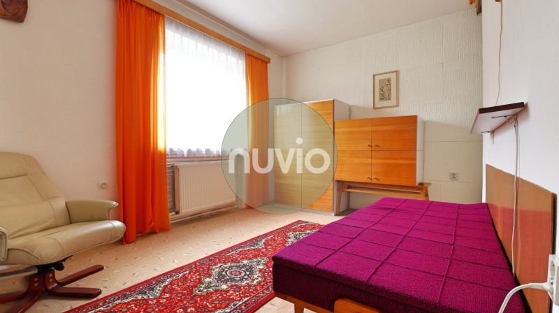 STRÁNE - 5 izbový rodinný dom na predaj - Izba v rodinnom dome so svetlom kreslom, nábytkom a výraznými oranžovými závesmi.