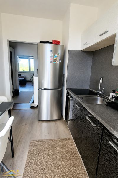 Prenájom: moderný 2-izbový byt s balkónom, Čadca SNP - Kuchyňa v 2-izbovom byte s chladničkou a podlahou s dreveným dekorom.