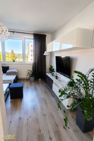 Prenájom: moderný 2-izbový byt s balkónom, Čadca SNP - Obývacia izba so pohovkou, stolom a televízorom, s podlahou s dreveným dekorom.