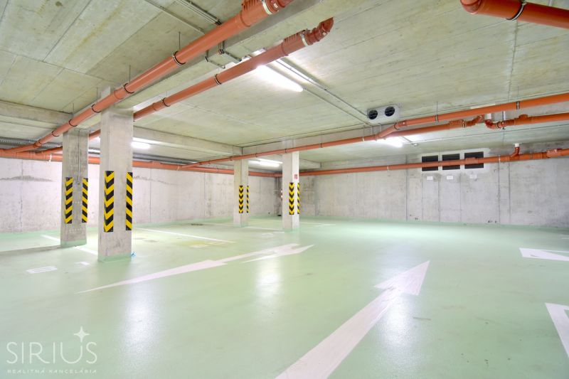UZBECKÁ, parkovacie miesto v garáži, novostavba Oppidum - Parkovacie miesta s betónovými stenami, rúrkami a bezpečnostnými značkami v Garážach.