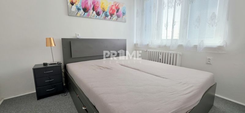  PRIESTRANNÝ 2i byt, BLUMENTÁL, CENTRUM, LOGGIA, Wilsonova ulica - Spálňa v 2-izbovom byte so sivou posteľou, obrazom a nočným stolíkom.