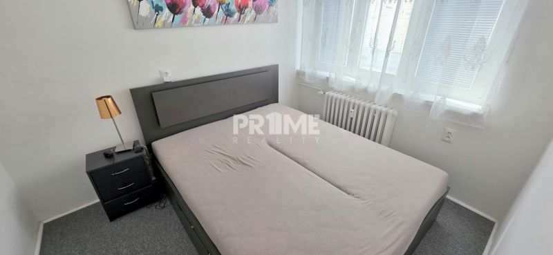  PRIESTRANNÝ 2i byt, BLUMENTÁL, CENTRUM, LOGGIA, Wilsonova ulica - Spálňa v 2-izbovom byte s manželskou posteľou, nočným stolíkom a obrázkom na stene.
