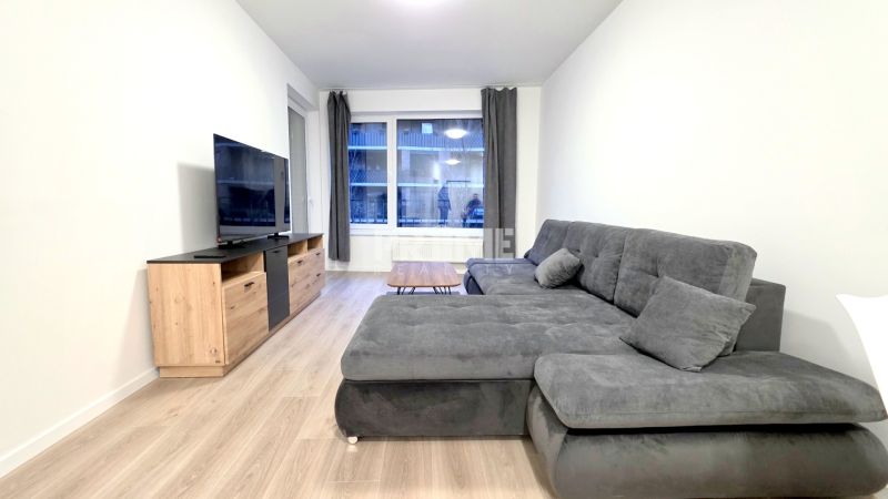 U NÁS !!! MODERNÝ 2i,NOVOSTAVBA, LOGGIA, Slnečnice UNIQ, Fialova ulica - Obývačka v 2-izbovom byte so sedačkou, TV a podlahou s dreveným dekorom.