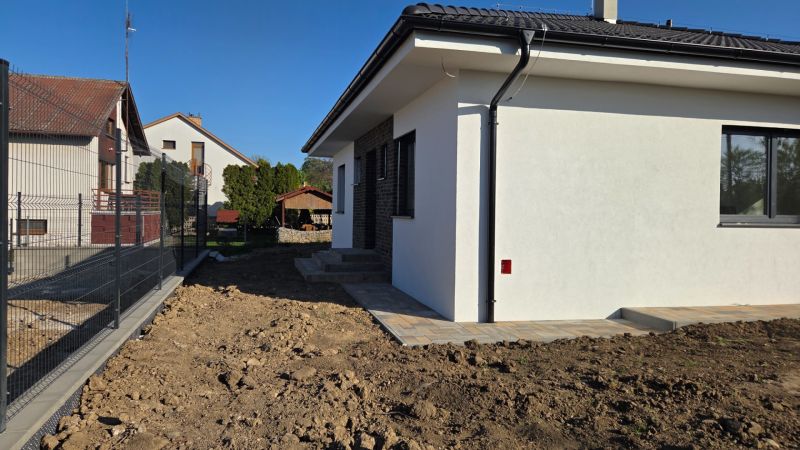 Bungalov v centre obce Cabaj v štandarde, Wágnerova ulica, Dom č.2 - Rodinný dom v Cabaj-Čápore s bielou fasádou, novým betónovým chodníkom a plotom.