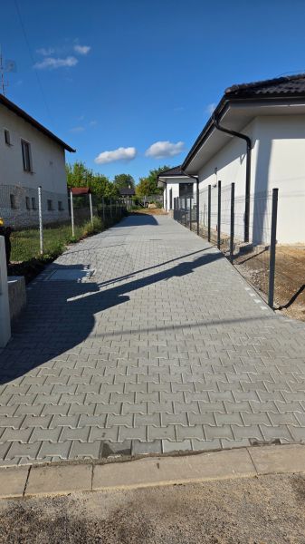 Bungalov v centre obce Cabaj v štandarde, Wágnerova ulica, Dom č.2 - Príjazdová cesta k rodinným domom v Cabaji-Čápore s oplotenými dvorami a modrou oblohou.
