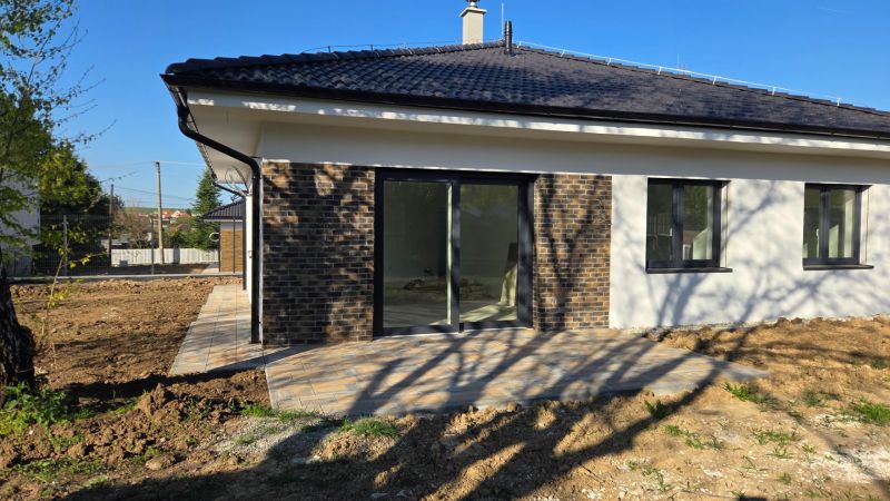 Bungalov v centre obce Cabaj v štandarde, Wágnerova ulica, Dom č.2 - Rodinný dom v Cabaj-Čápore s tehlovou fasádou, posuvnými dverami a dlažbou na terase.