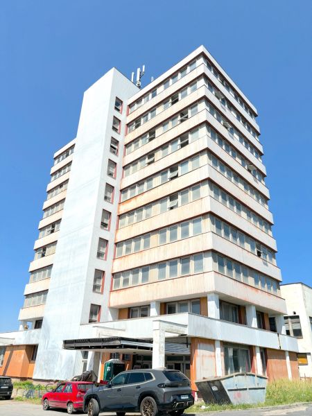 FORVIN TOWER - Predaj administratívnej budovy, Veľký Krtíš - Výšková budova Liaz s autami zaparkovanými na ulici, zvlášť zaujímavá nehnuteľnosť.