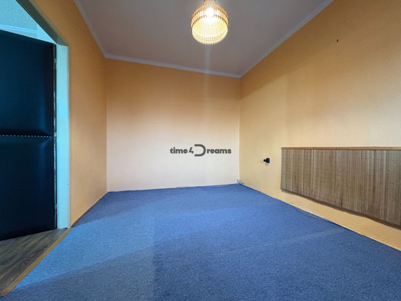 Na predaj: CENTRUM 3 izb.byt + LOGGIA + KLÍMA + PIVNICA - Izba s modrým kobercom a oranžovými stenami v 3-izbovom byte.
