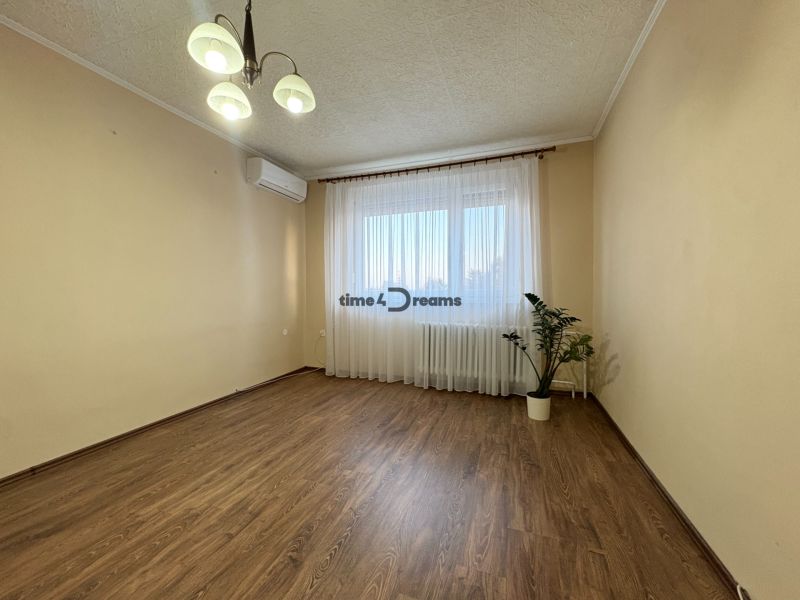 Na predaj: CENTRUM 3 izb.byt + LOGGIA + KLÍMA + PIVNICA - Obývačka v 3-izbovom byte s podlahou s dreveným dekorom a svetlým interiérom.