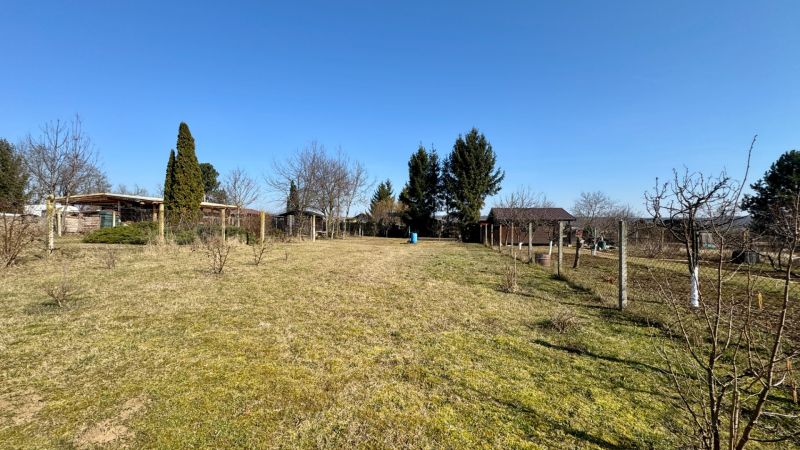 NA PREDAJ Pozemok Párovské Háje - Záhrady v Párovských Hájoch s trávnatou plochou, stromami a modrou oblohou.