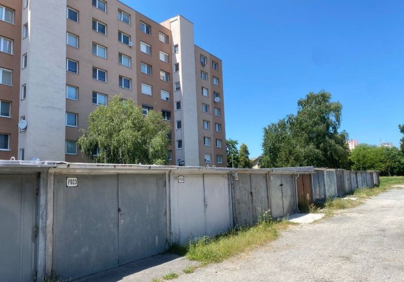 PREDAJ - Garáž v Stupave na ulici Železničná - Garáže na Železničnej ulici v Stupave, vedľa obytného domu pod modrou oblohou.