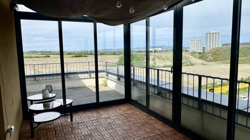 4 izbový byt 150 m2 novostavba Petržalka v Slnečniciach  s terasou, 2x - Zasklená terasa s podlahou s dreveným dekorom v 4-izbovom byte, s výhľadom na panorámu.