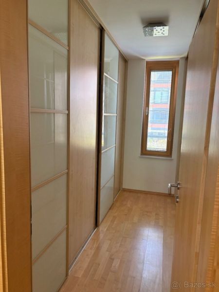4 izbový byt 120 m2 Ružová dolina, Ružinov, 1x podzemné´parkovanie - Chodba s veľkými vstavanými skriňami a podlahou s dreveným dekorom v 4-izbovom byte.