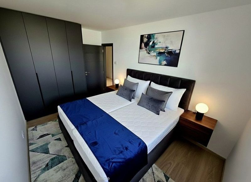 PREDAJ ELEGANTNÝ 2-IZBOVÝ BYT S BALKÓNOM A PARKOVANÍM V RAČI - Spálňa v 2-izbovom byte s dvojlôžkom, tmavými skriňami a podlahou s dreveným dekorom.