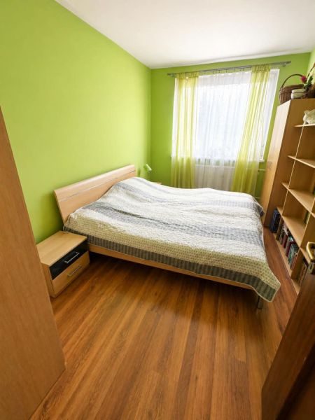 3 izbový byt 75m2, ul.Bruselská, Košice- Ťahanovce - Spálňa v 3-izbovom byte so zelenými stenami a podlahou s dreveným dekorom.