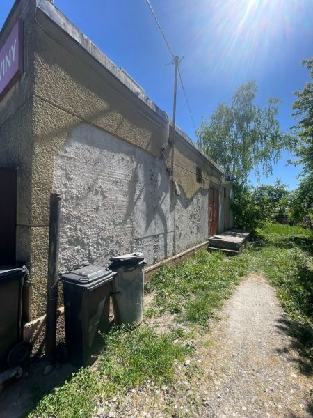 Postavte si dom alebo podnikajte - Exteriér budovy v Ondrejovciach s trávnatým okolím a odpadkovými košmi.