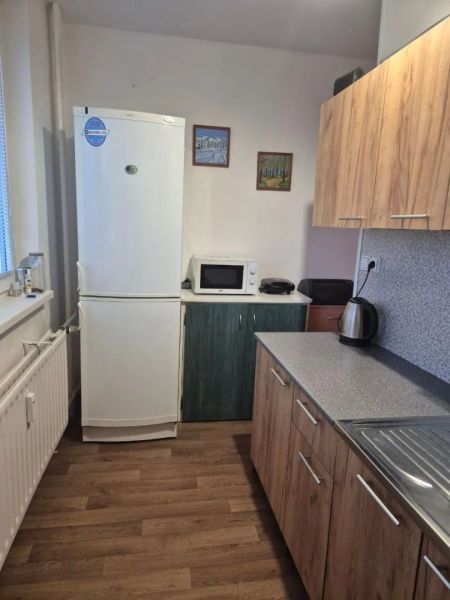Prenájom 2 izbový byt Poprad - loggia - Kuchyňa s podlahou s dreveným dekorom, kuchynskou linkou a spotrebičmi v 2-izbovom byte.