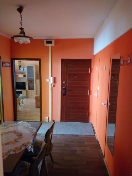 Prenájom 2 izbový byt Poprad - loggia - Chodba v 2-izbovom byte s oranžovými stenami a podlahou s dreveným dekorom.
