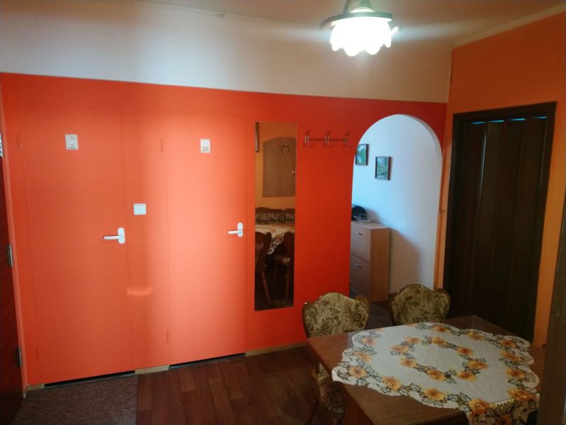 Prenájom 2 izbový byt Poprad - loggia - Jedáleň v 2-izbovom byte s oranžovou stenou, podlahou s dreveným dekorom a oblúkom.
