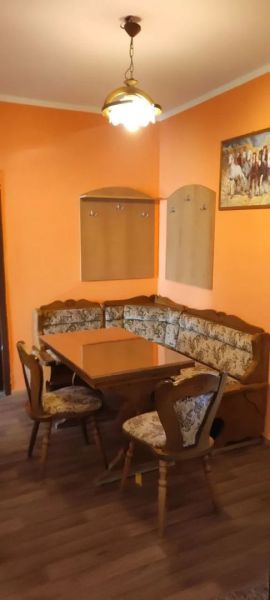 Prenájom 2 izbový byt Poprad - loggia - Kuchynský kút so sedačkou v 2-izbovom byte, podlaha s dreveným dekorom, oranžové steny.