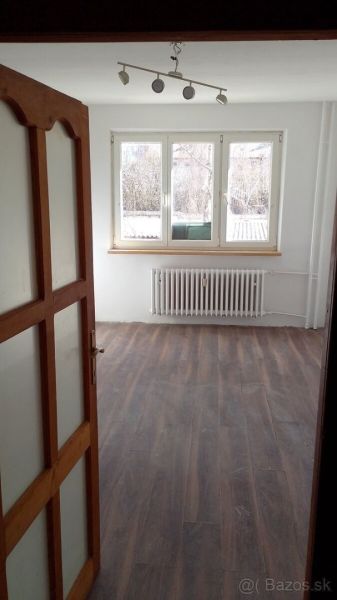 Na predaj priestranný 2-izbový byt 56m2– Košice, Lomená ulica - Interiér 2-izbového bytu s podlahou s dreveným dekorom a veľkým oknom.