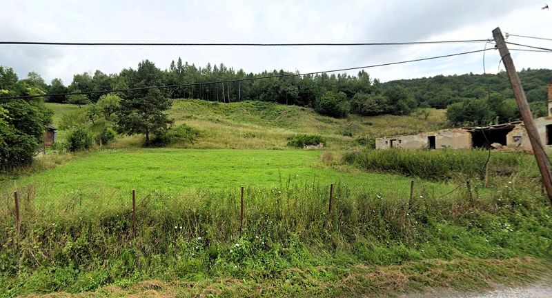 Na predaj stavebné pozemky - 7 500 m² v obci Zubné. - Zvláštne nehnuteľnosti v Zubnom: rozpadnutá stavba, tráva, stromy a kopec v pozadí.