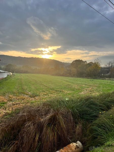 Na predaj pozemok o rozlohe - 4 070 m² vhodný na výstavbu rodinného do - Západ slnka nad zelenými pozemkami v Slovenskej Volovej, ideálnymi na bývanie.