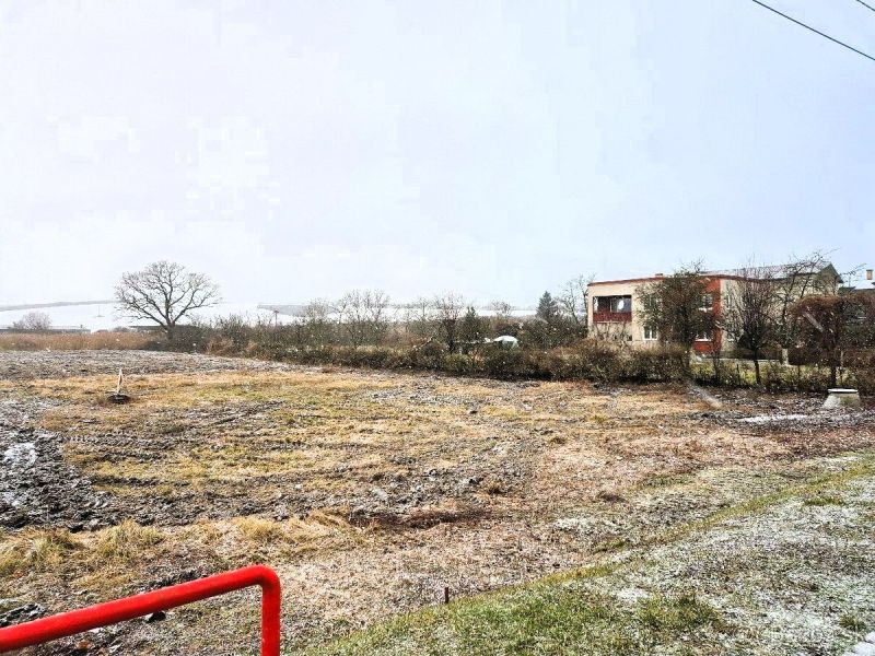 Na predaj stavebný pozemok o rozlohe 1440 m² v obci Soľ. - Zasnežené pozemky na bývanie vo Vranove nad Topľou s viditeľnou zástavbou v pozadí.