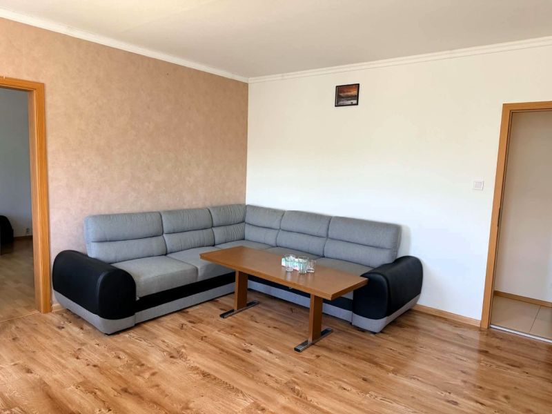Na predaj zrekonštruovaný a kompletne zariadený 3 - izbový byt  v Hume - Šedá rohová pohovka s konferenčným stolíkom na podlahe s dreveným dekorom v 3-izbovom byte.