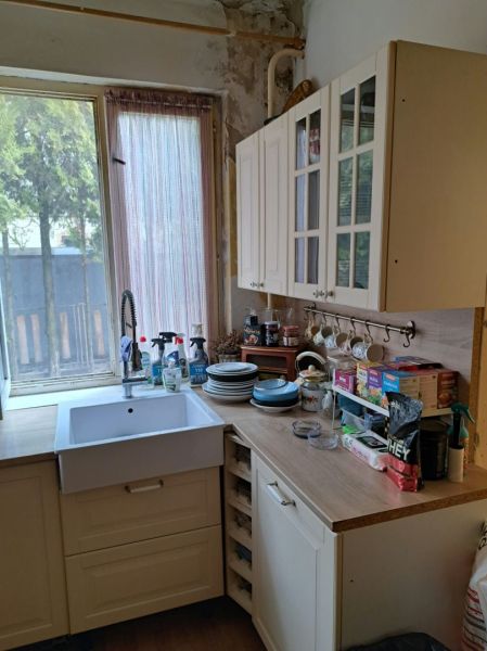 Dom na bývanie a podnikanie na 15 ár. pozemku 35 km od BA - Kuchyňa s bielymi skrinkami, dreveným dekorom a oknom prepúšťajúcim vonkajšie svetlo.