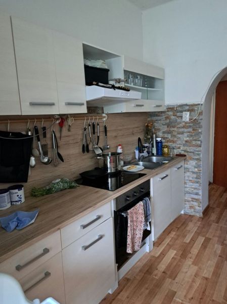 Dom na bývanie a podnikanie na 15 ár. pozemku 35 km od BA - Kuchyňa s podlahou s dreveným dekorom v rodinnom dome, kachličková stena, biely nábytok.