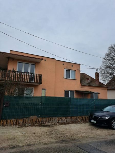 Dom na bývanie a podnikanie na 15 ár. pozemku 35 km od BA - Rodinný dom v Orechovej Potôni s oranžovou fasádou, balkónom a autom pred ním.